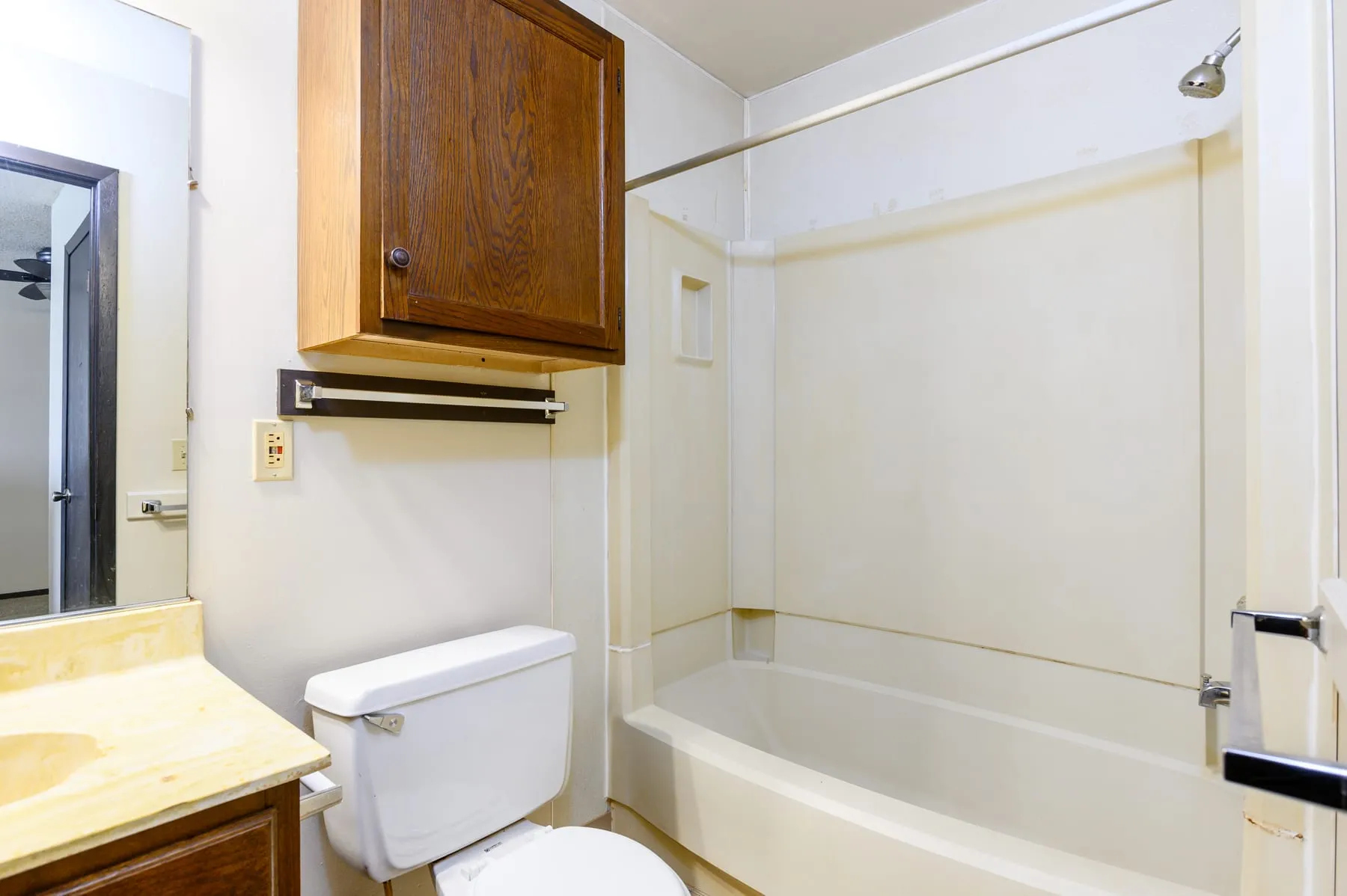 Original studio bathroom with tub, vanity and oak cabinetry.