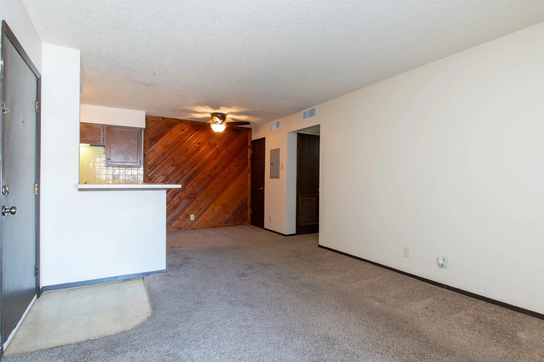 A two bedroom at Stoneybrook in its original condition, carpeted, with a cedar plank accent wall.