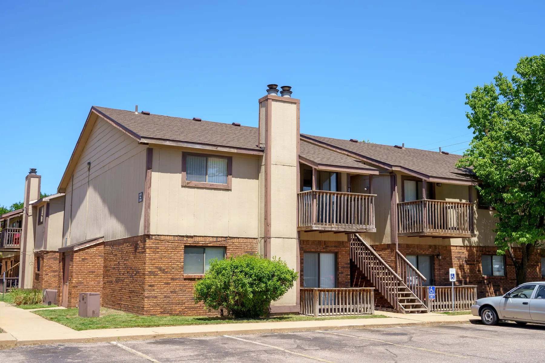 Brick and siding apartment building at Stoneybrook with mature landscaping.