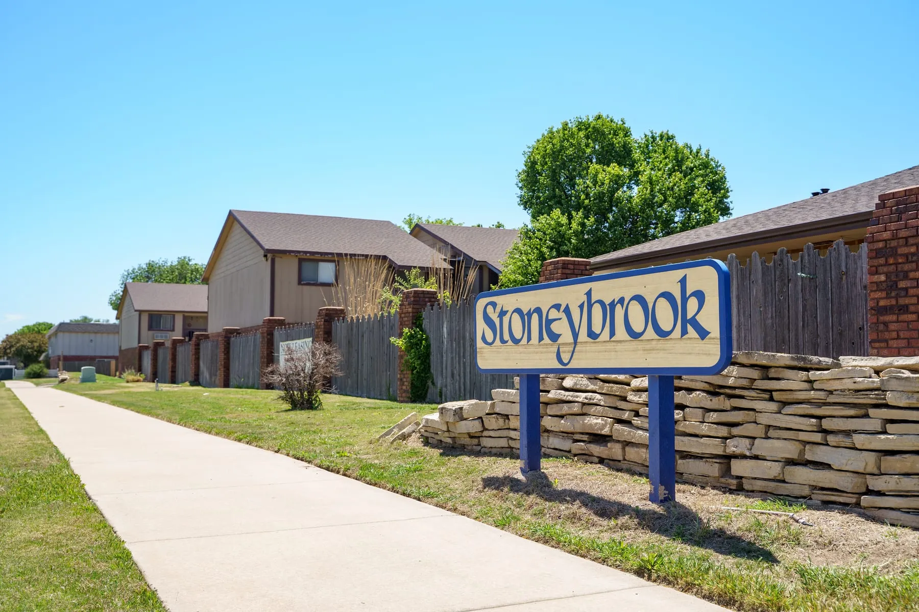 Property entrance at Stoneybrook with the monument sign and mature trees.