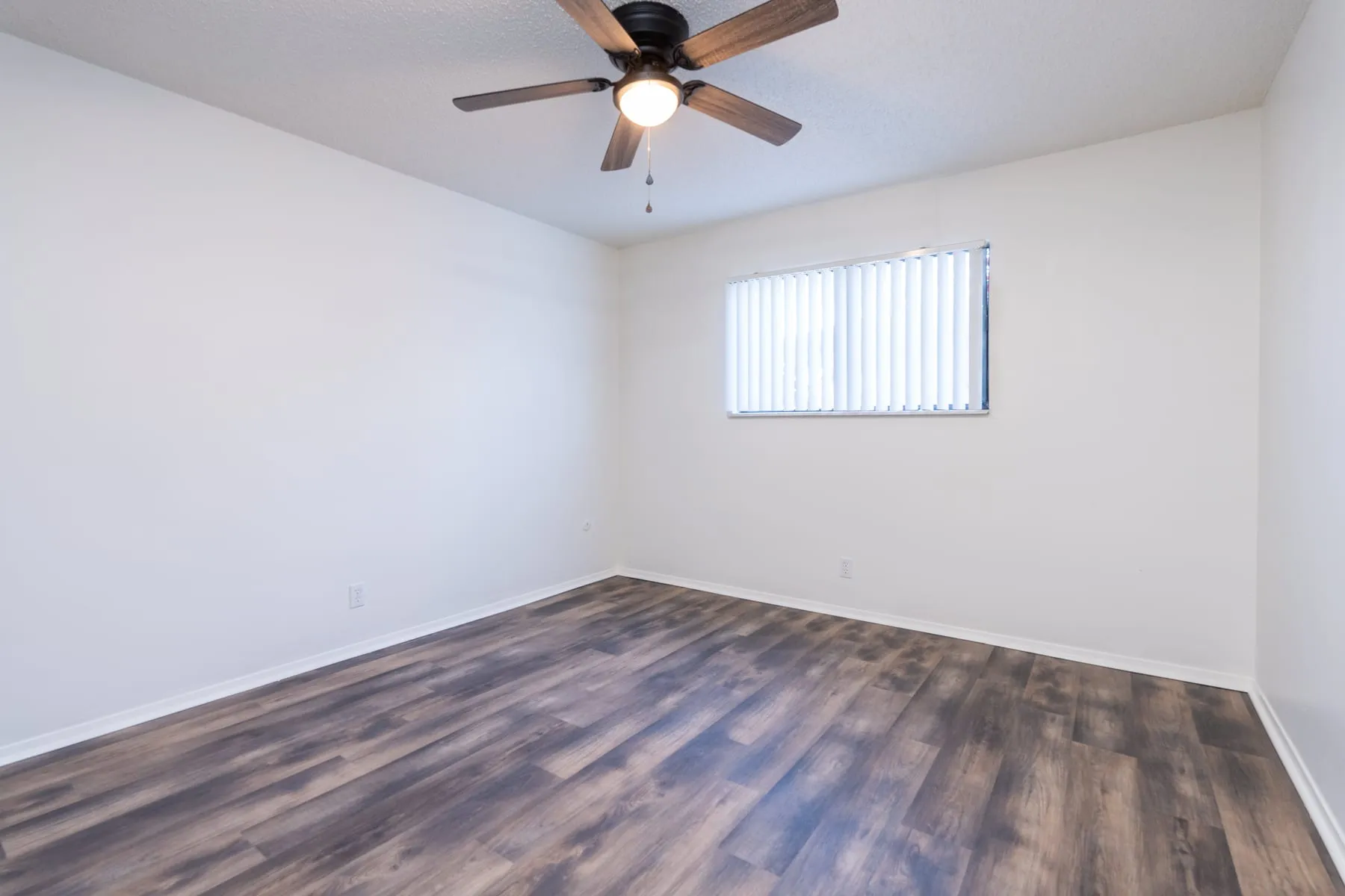 One bedroom sleeping area with ceiling fan, window and plank flooring.