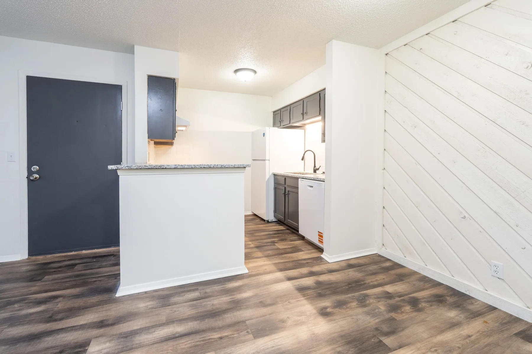 One bedroom kitchen with graphite cabinetry seen from the living area.