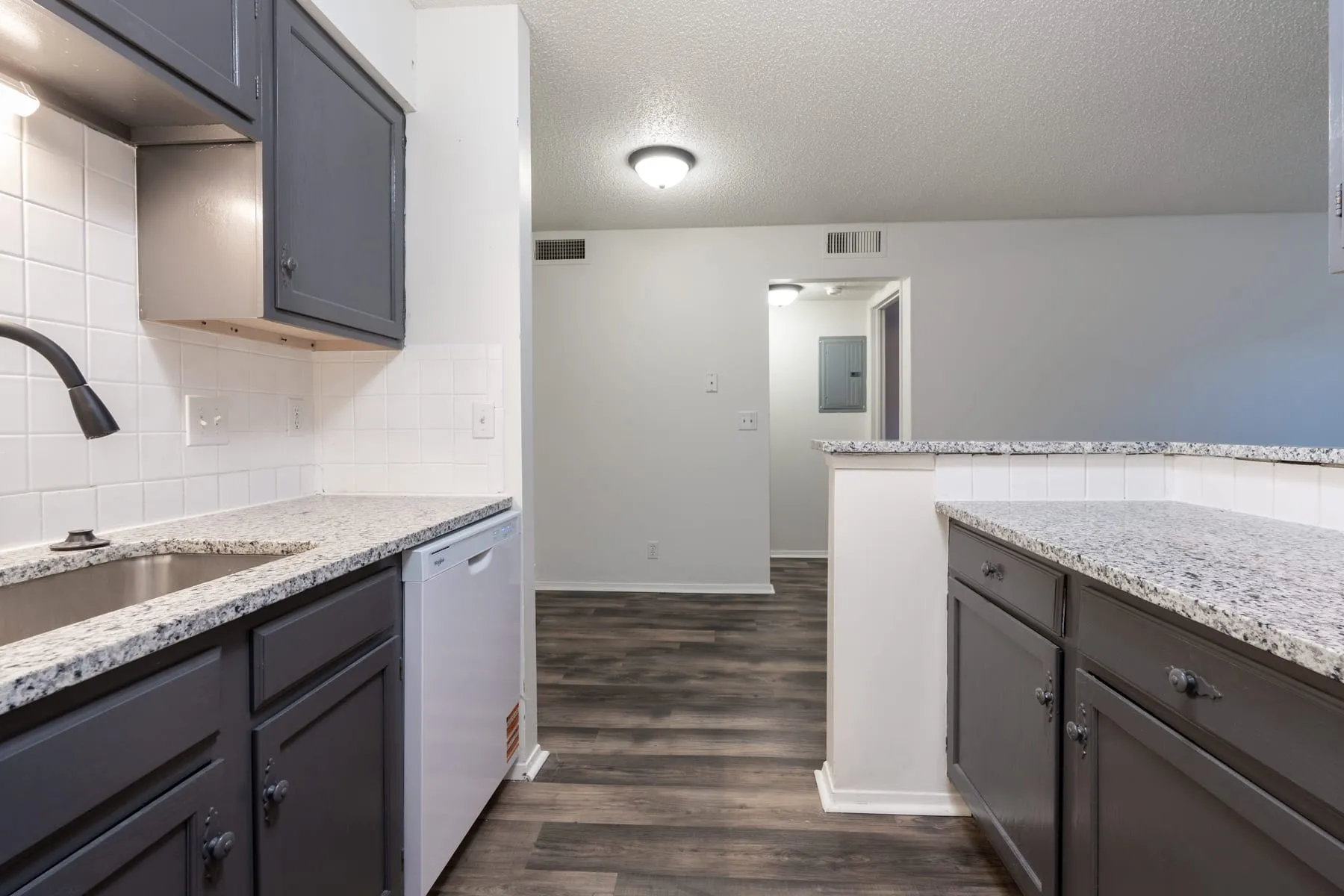 One bedroom kitchen with dishwasher, granite counters and subway tile backsplash.