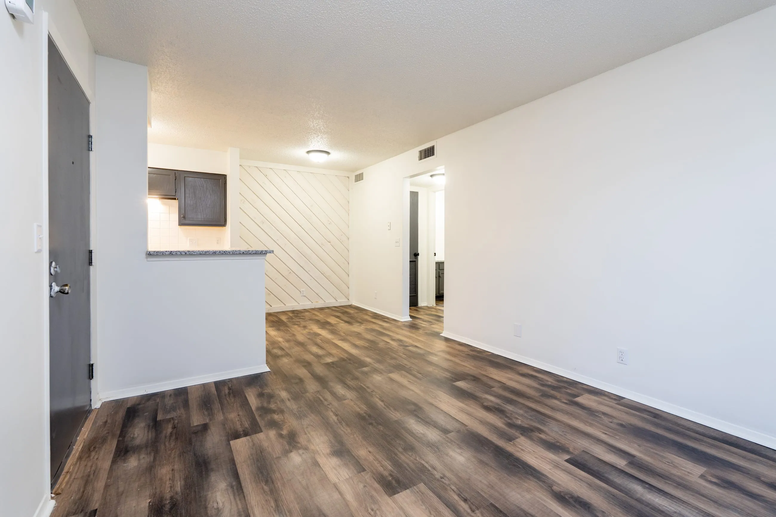Renovated one bedroom living area at Stoneybrook with plank flooring and a white diagonal plank accent wall.