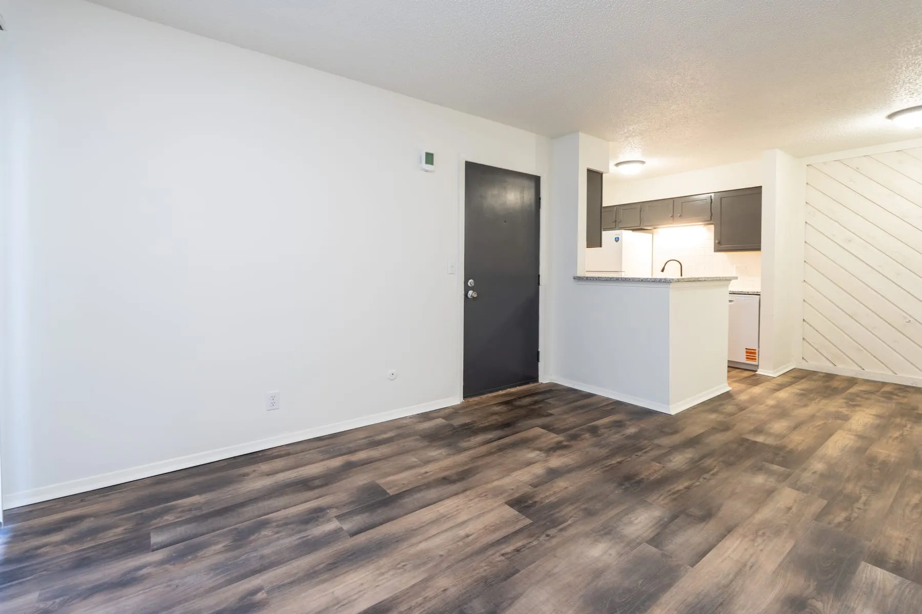 One bedroom living area looking toward the entry and kitchen pass-through.
