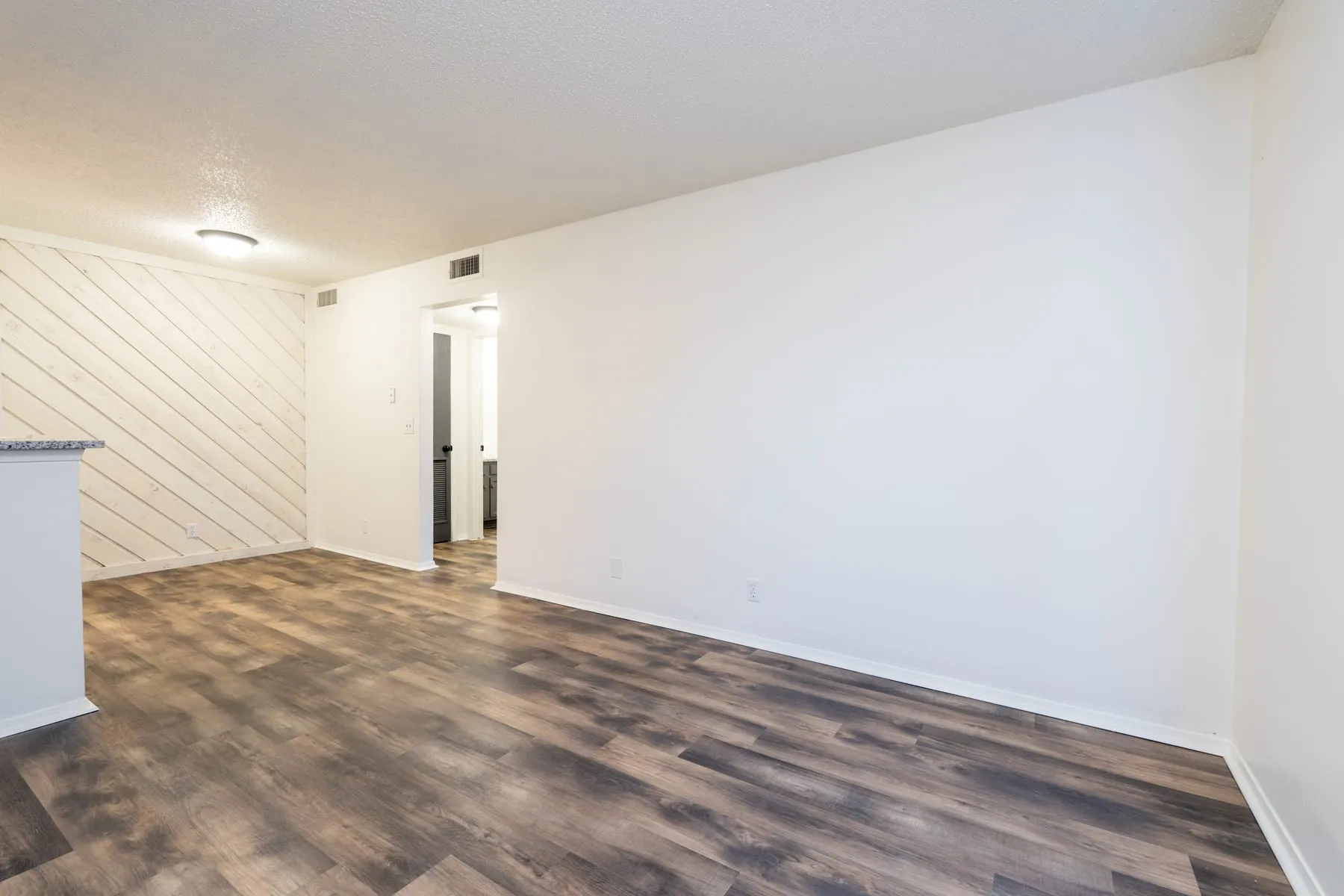 One bedroom living area with the kitchen peninsula on the left and the accent wall beyond.