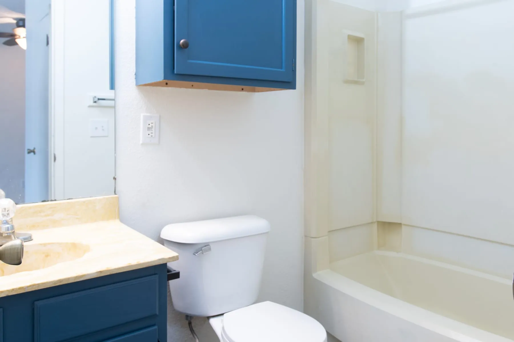 Studio bathroom with tub and shower surround beside a vanity.
