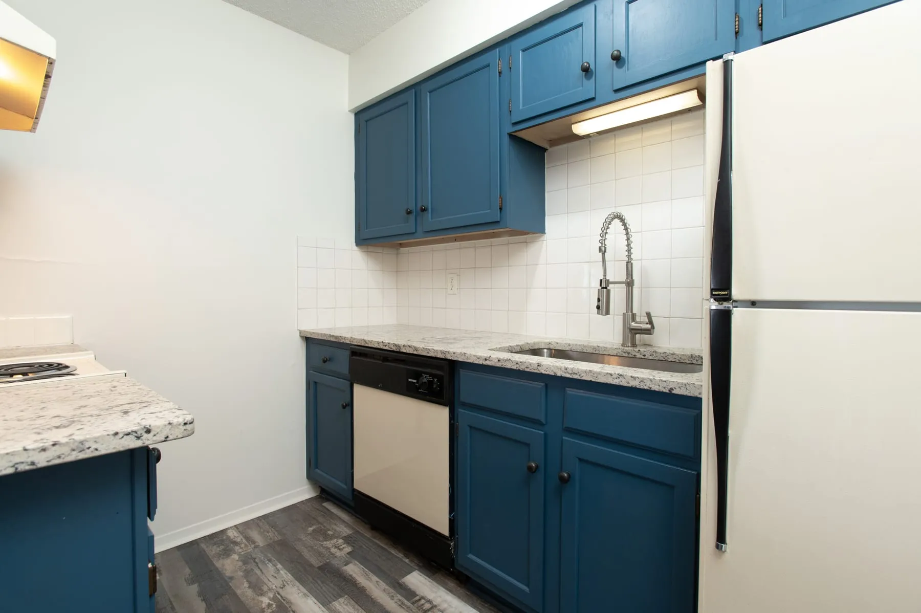 Studio kitchen with dishwasher, granite counters and full-size refrigerator.