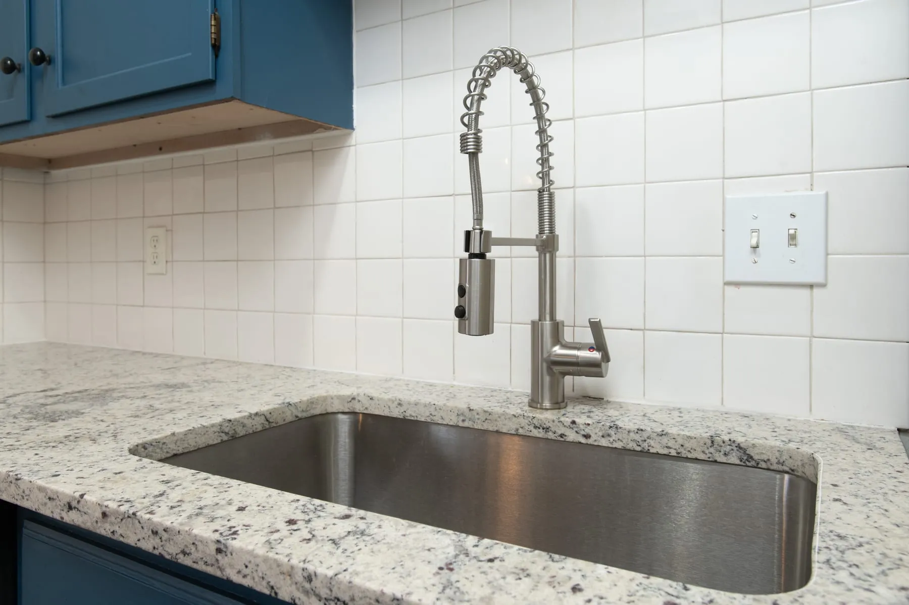 Close view of a stainless sink and matte black pull-down faucet on granite.