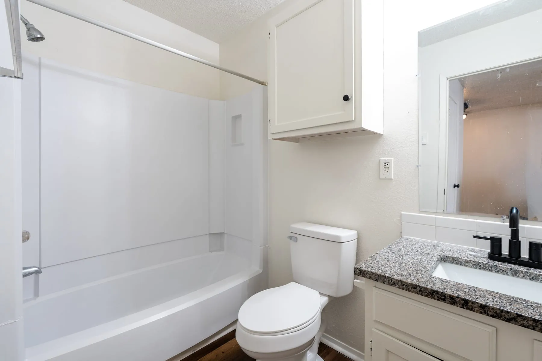 Renovated studio bathroom with a granite-topped vanity and matte black fixtures.