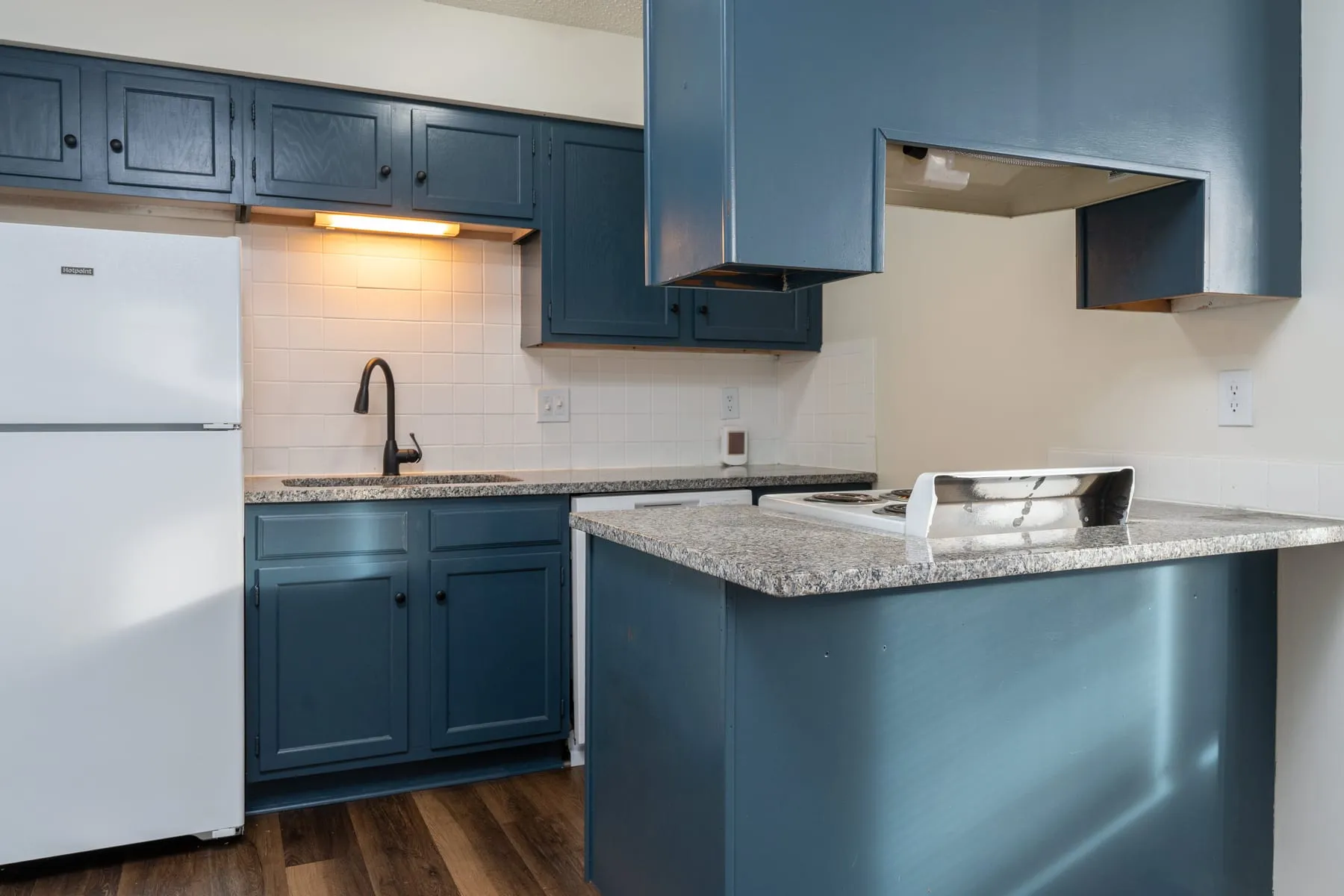 Granite counters and white subway tile backsplash in a renovated studio kitchen.