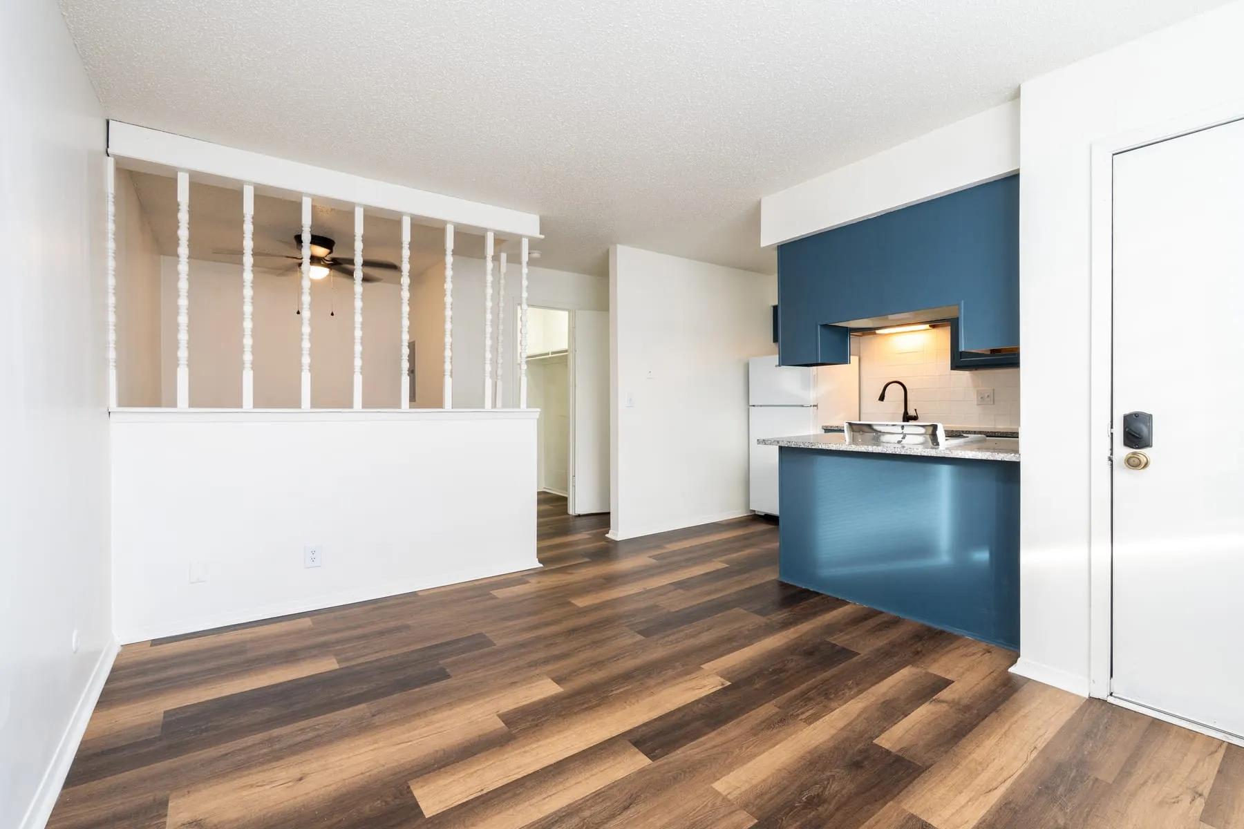 Open studio living area with plank flooring running through to the kitchen peninsula.