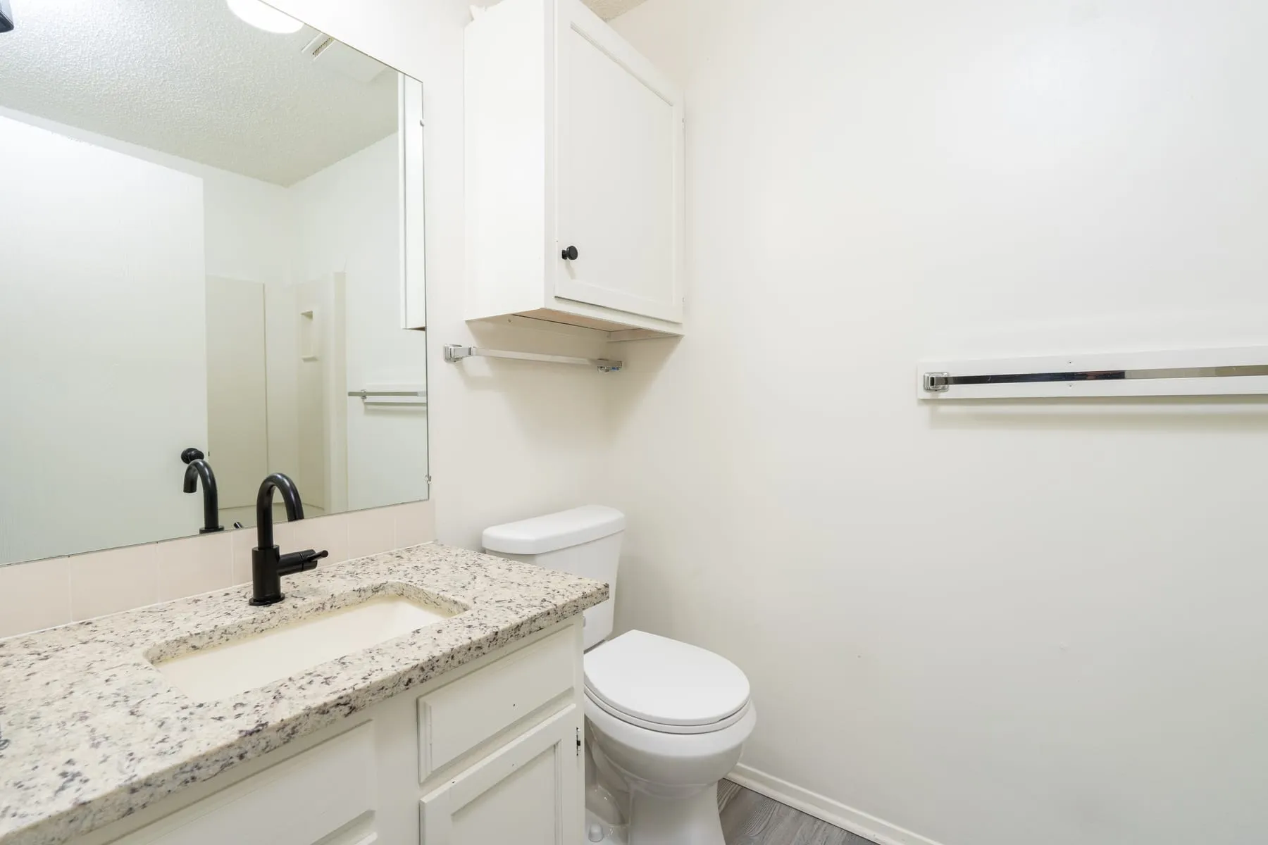 Two bedroom bathroom with a granite vanity, wide mirror and matte black fixtures.