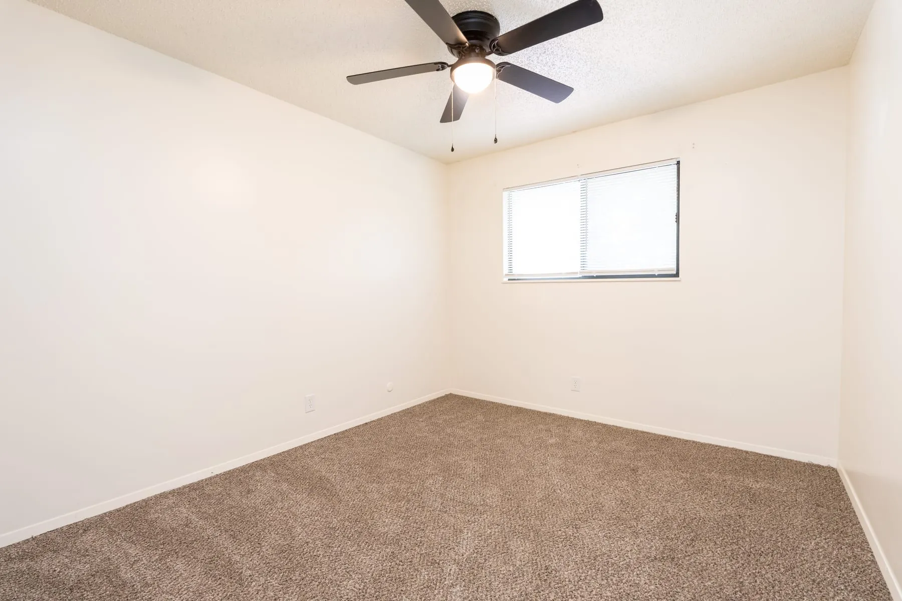 Carpeted two bedroom sleeping area with a ceiling fan and window.