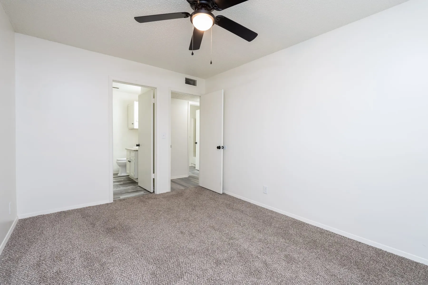 Carpeted bedroom looking through to the hallway and bathroom.