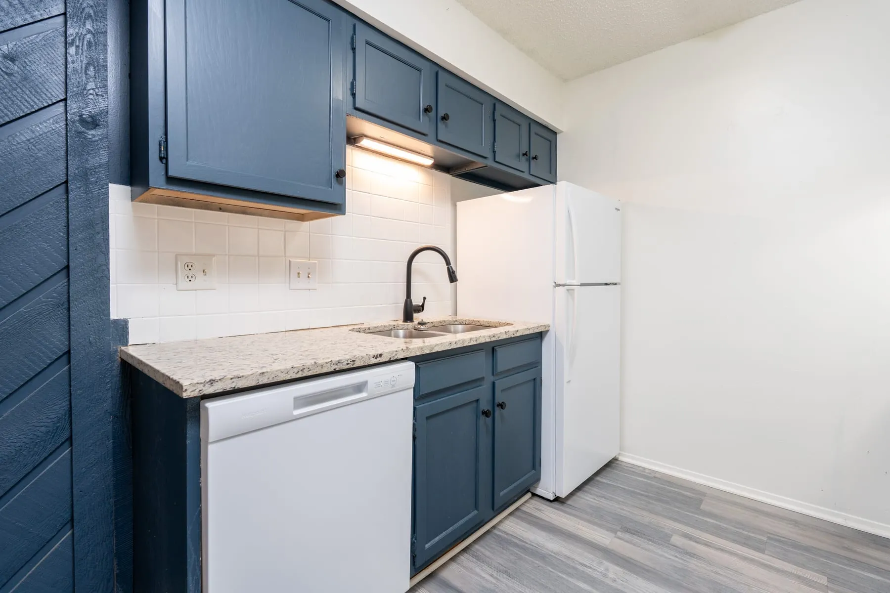 Two bedroom kitchen with slate-blue cabinetry, granite counters and a dishwasher.