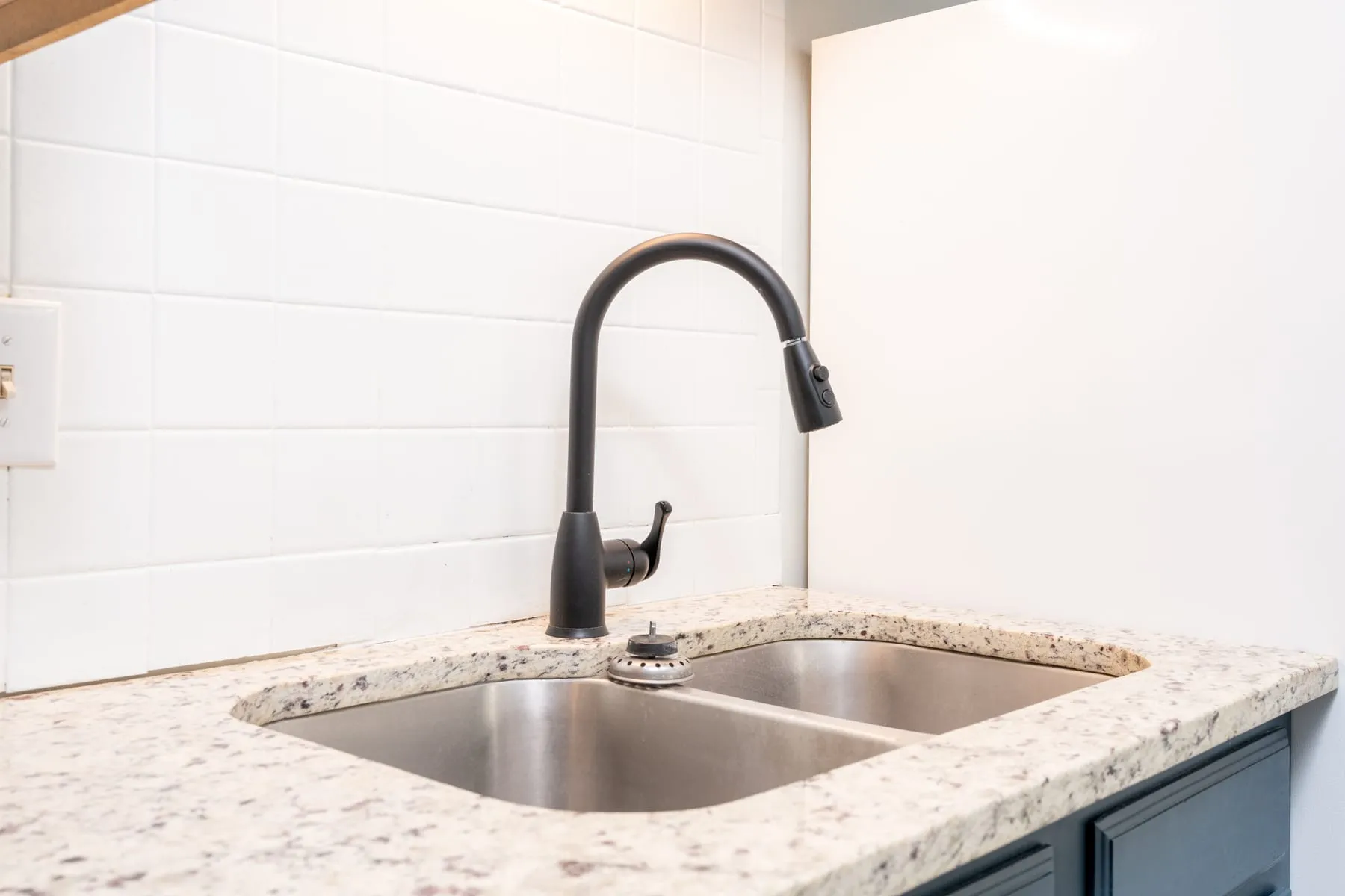 Double stainless sink with a matte black faucet on granite counters.