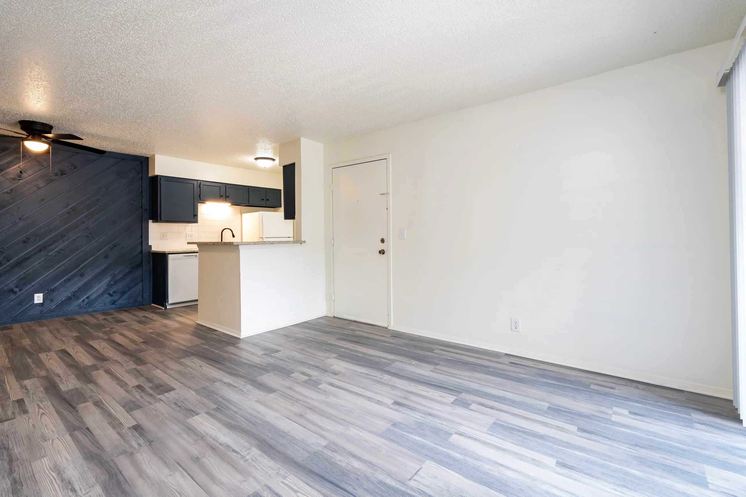 Renovated two bedroom living area at Stoneybrook with driftwood-tone plank flooring and a stained diagonal plank accent wall.