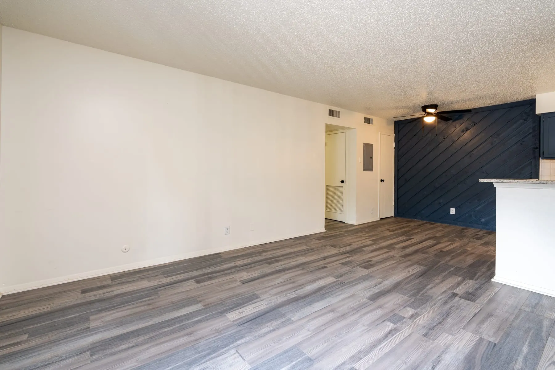 Two bedroom living area looking toward the kitchen and accent wall.